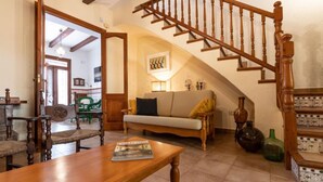 Ein gemütliches Wohnzimmer mit einer Holztreppe, einem Sofa, einem Couchtisch und einem Esstisch.
