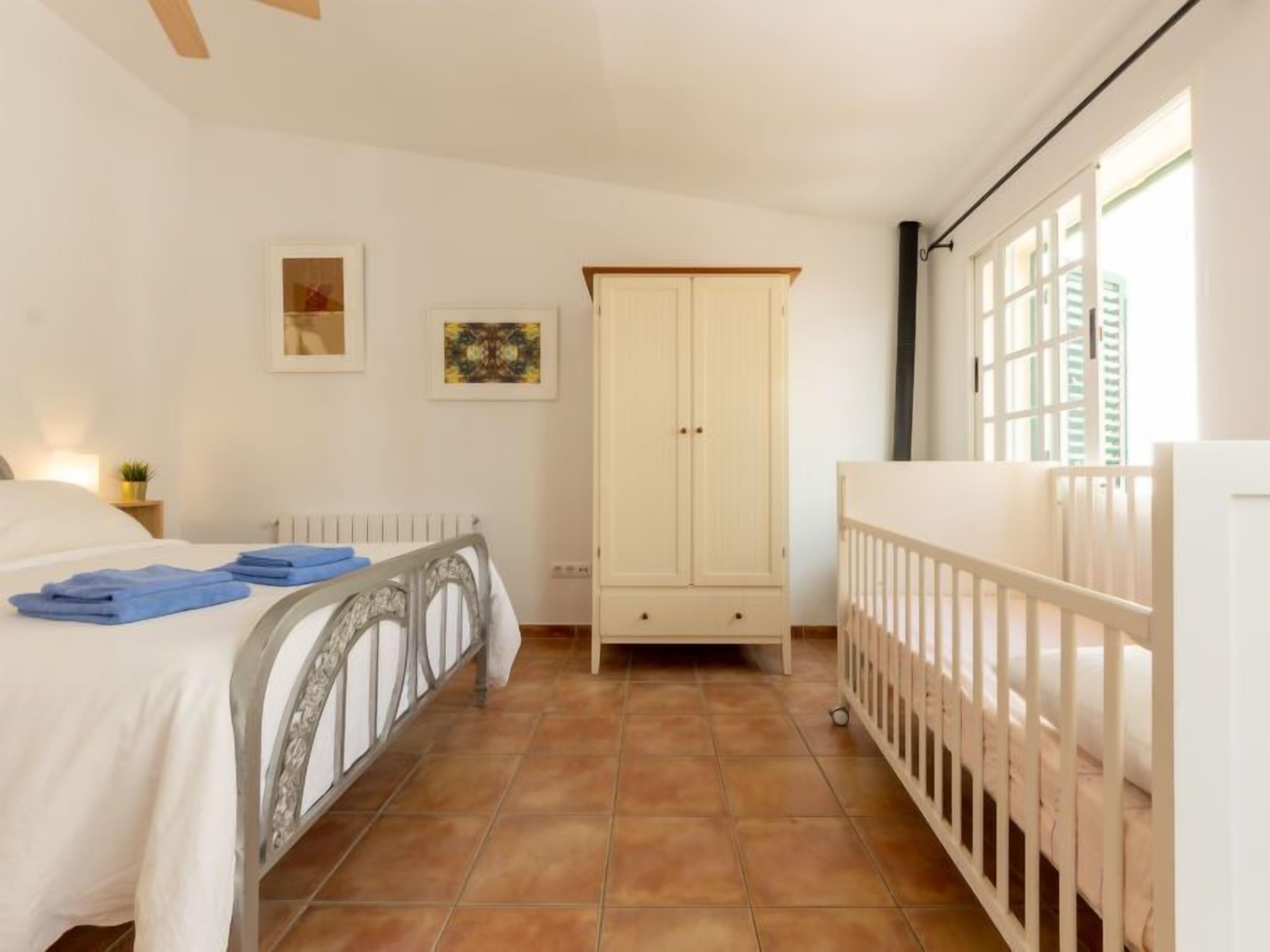 A bedroom with a bed, a crib, a wardrobe, and a radiator.