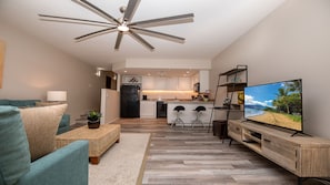 Cozy living space with a central kitchen area, featuring a flat-screen TV, sofa, and coffee table.