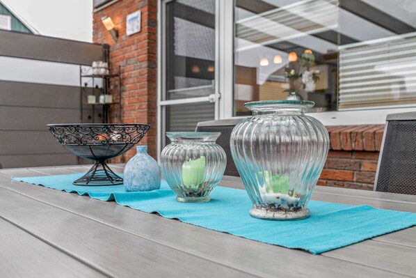 A table with decorative glass vases and a metal bowl on a blue placemat.