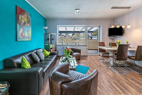 A modern living room with a sofa, chairs, a coffee table, and a TV.
