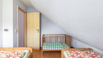 Una stanza con due letti di legno, una porta e un soffitto spiovente.