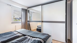 A bedroom with a bed, a sliding door, a window, and a radiator.