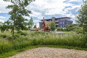 A playground with climbing structures and a building with multiple windows in the background.