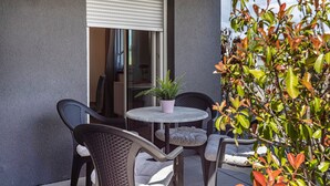 A patio with two chairs, a small round table, and a potted plant.