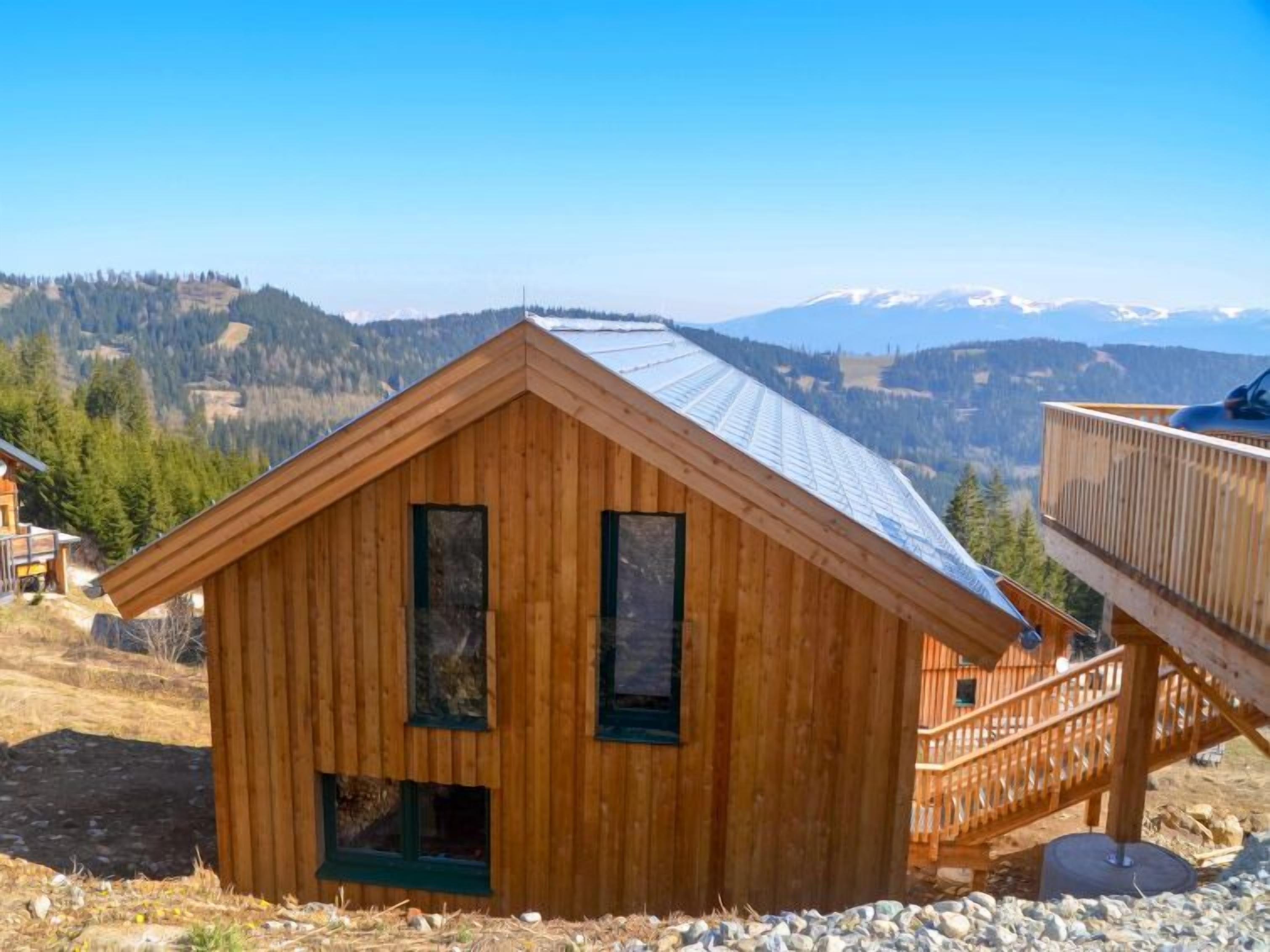 Une cabane en bois avec un toit en métal, un balcon et une vue sur les montagnes.