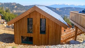 Une cabane en bois avec un toit en métal, un balcon et une vue sur les montagnes.