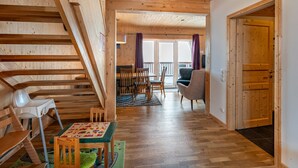 Un intérieur en bois avec un escalier, un coin repas et une vue sur l’extérieur.