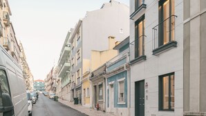 A street with buildings on both sides, a van parked on the left, and a clear sky. - STUPENDO-1 BR-Center- Air conditioning (Lisboa)