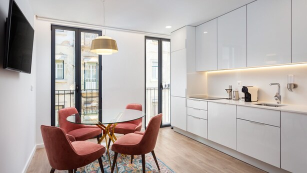 A modern kitchen with white cabinets, a round glass table, and pink chairs. - STUPENDO-1 BR-Center- Air conditioning (Lisboa)