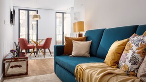 A modern living room with a blue sofa, red chairs, a glass coffee table, and a lamp. - STUPENDO-1 BR-Center- Air conditioning (Lisboa)