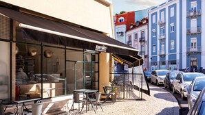 A cafe with outdoor seating, a black awning, and a glass storefront. - STUPENDO-1 BR-Center- Air conditioning (Lisboa)