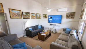 A living room with a grey sofa, a coffee table, a TV, and framed pictures on the wall. - Hawker Bed and Breakfast (Hawker)