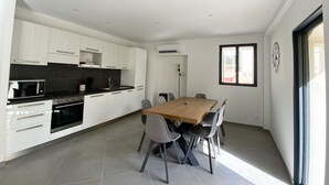 Una cucina moderna con mobili bianchi, un piano di lavoro nero e un'area pranzo con tavolo in legno e sedie grigie.
