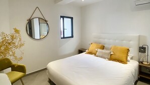 Una camera da letto moderna con un letto grande, uno specchio rotondo, un tavolino e una sedia.