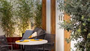 A dining area with a round table, black chairs, and a wall adorned with bamboo plants. - STUPENDO-2BR- Patio, Refresh Pond-A/C-Center (Lisboa)