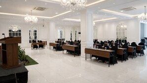 A spacious conference room with multiple tables and chairs, large windows, and chandeliers. - Maestro Hotel Pontianak (Pontianak)
