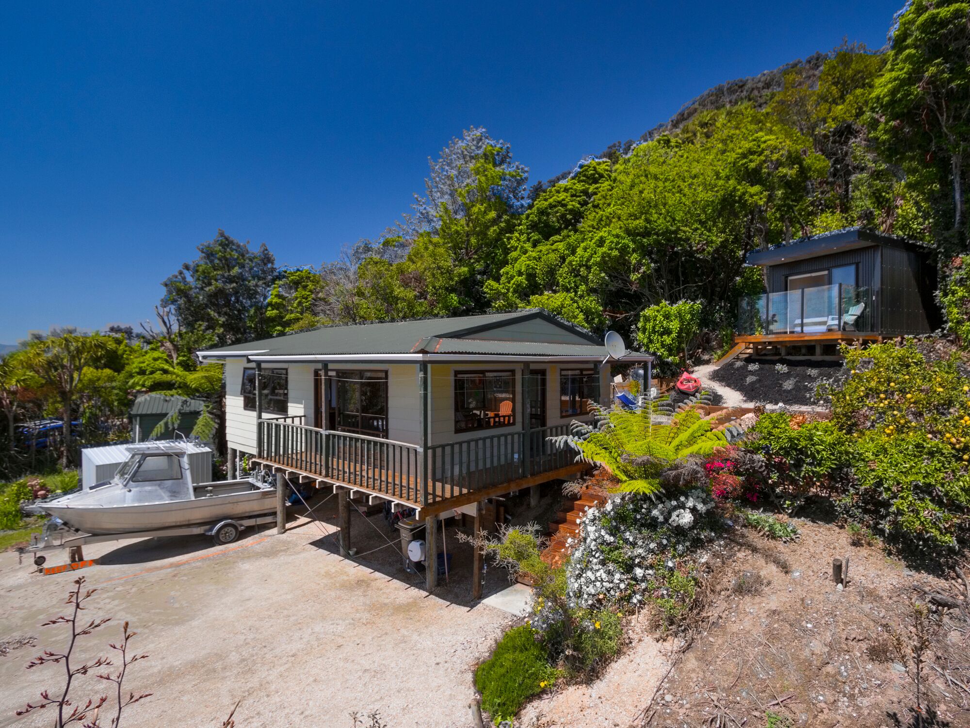 A modern house with a deck, a boat, and lush garden.