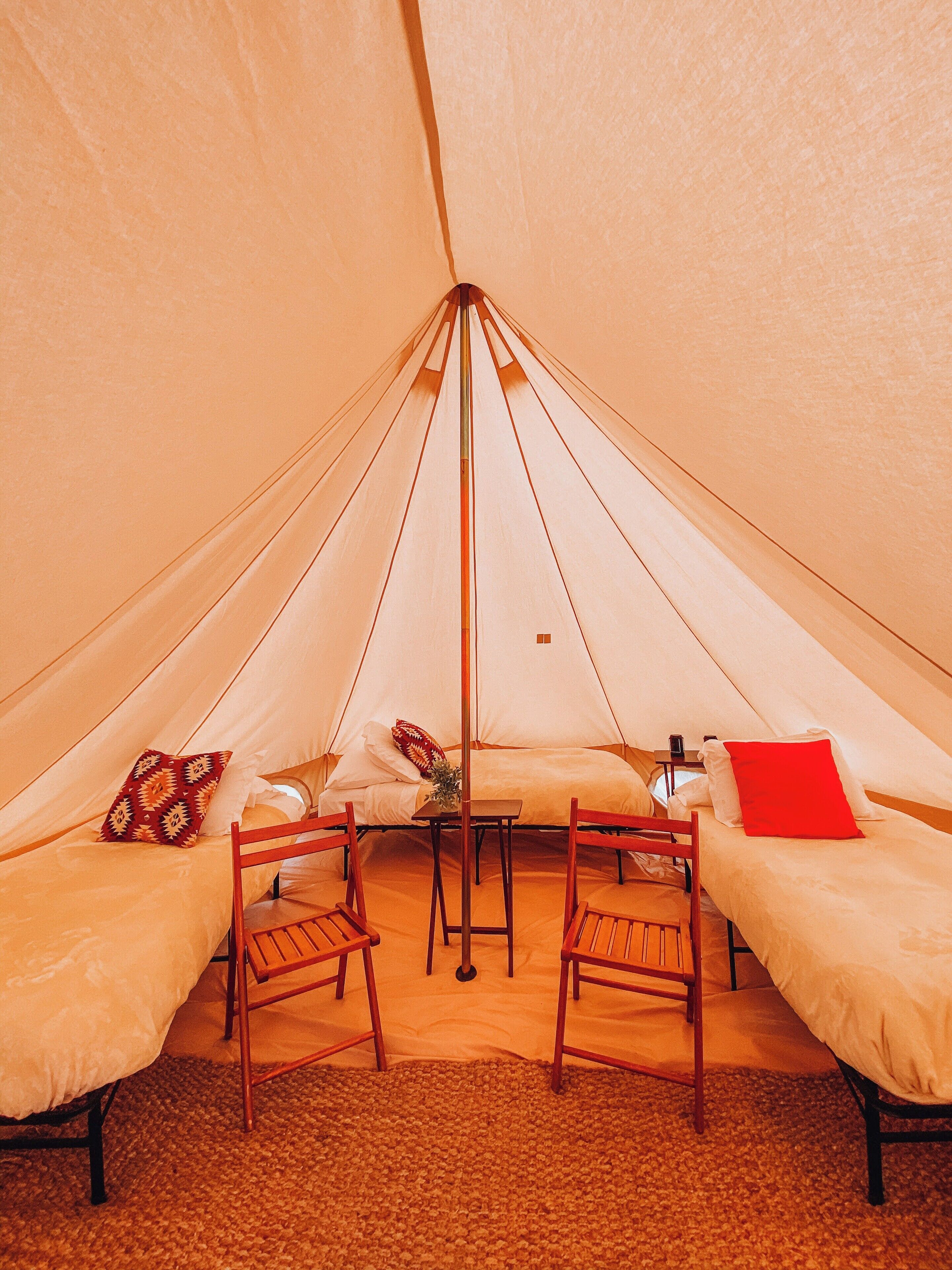 A tent with two beds, a table, and chairs.