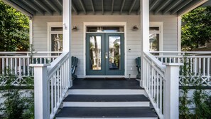 A porch with a double door, white railings, and steps leading to a house.