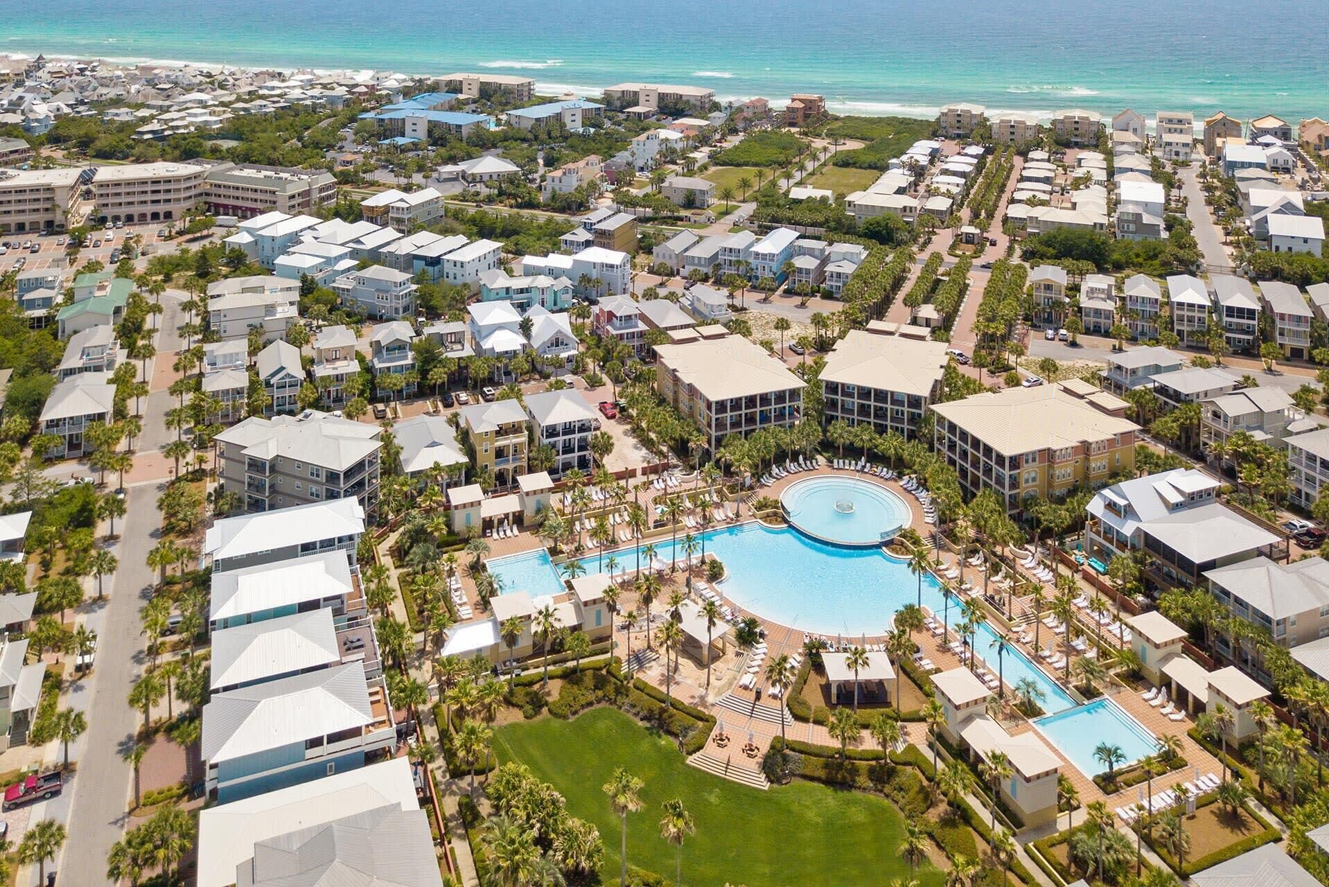 Ein Resort mit mehreren Gebäuden, einem zentralen Swimmingpool und Blick auf einen Strand.