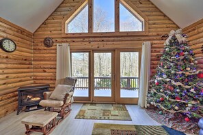 Ein rustikaler Blockhausausschnitt mit Kamin, Weihnachtstanne und großem Fenster.