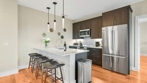 A modern kitchen with a central island, stainless steel appliances, and wooden flooring. - Luxury Condo, Downtown Asheville (Asheville)