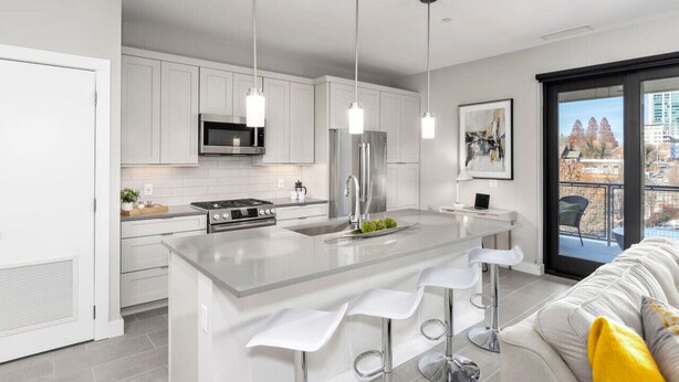 A modern kitchen with white cabinets, stainless steel appliances, and a central island with bar stools.