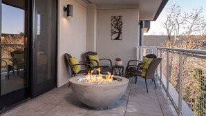 A balcony with a fire pit, outdoor seating, and a view of the surrounding area.