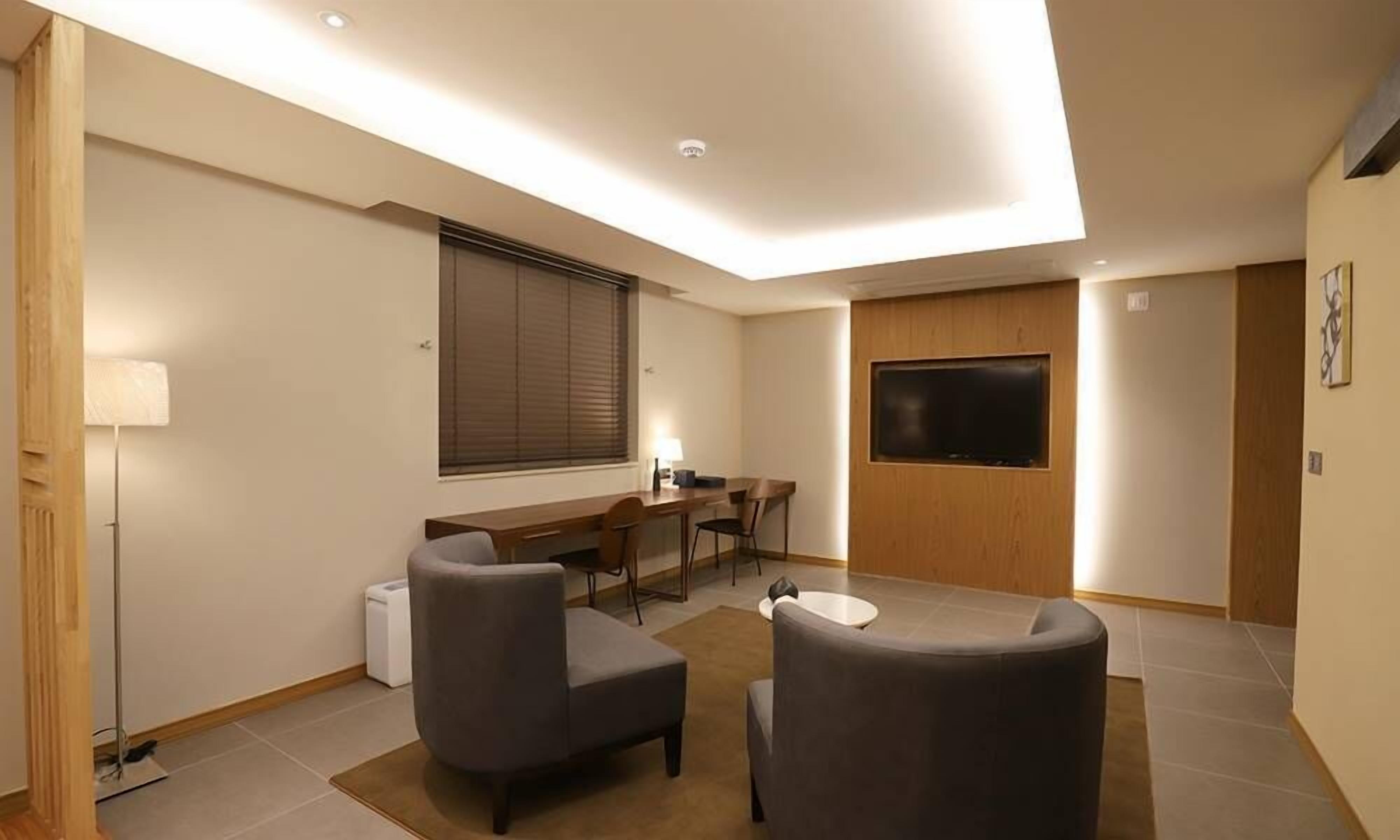Una habitación moderna con zona de comedor, televisión de pantalla plana y sofá.
