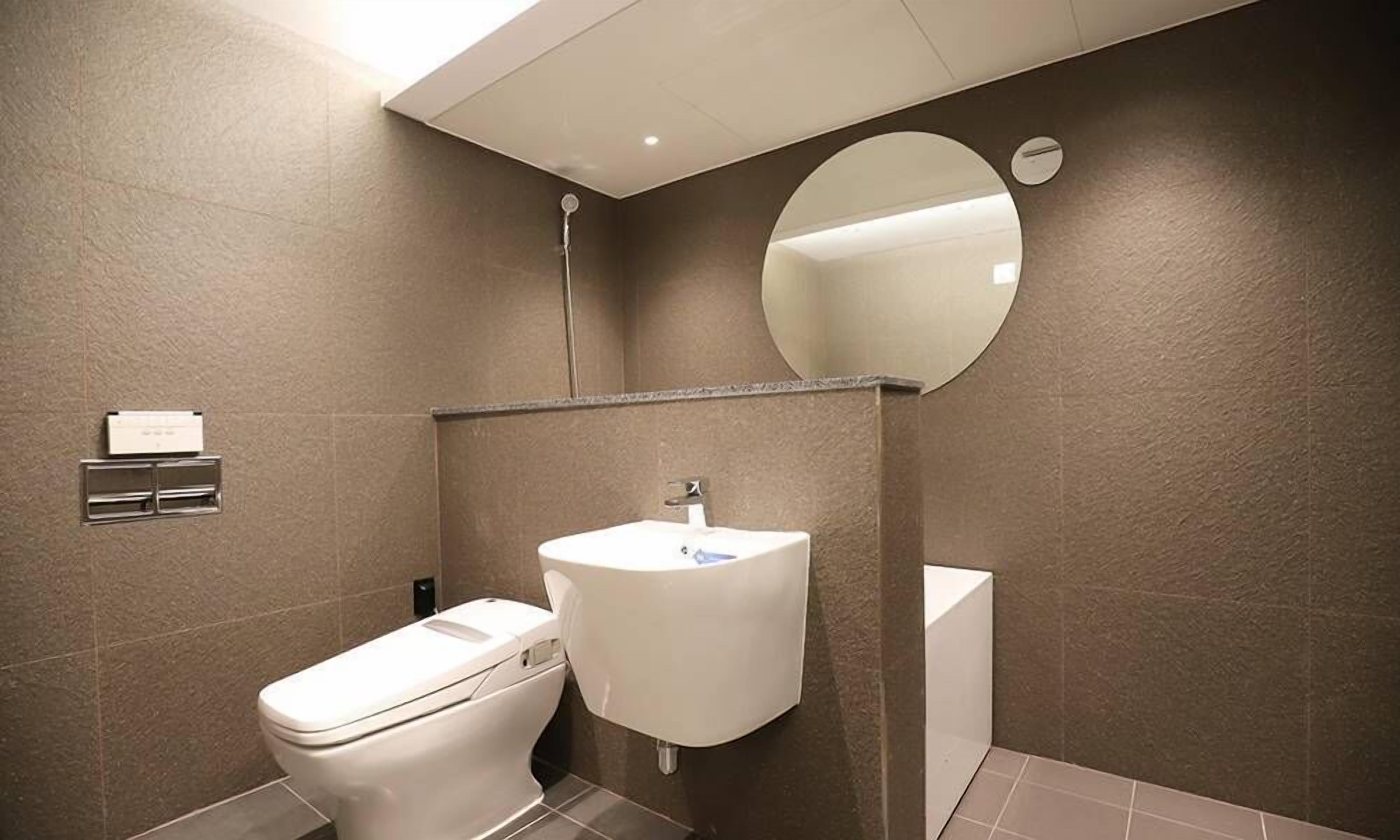 Un baño con inodoro, lavamanos y espejo.