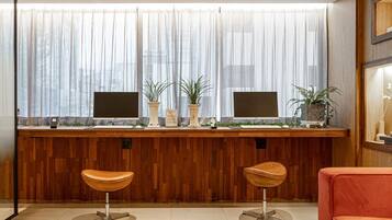 A reception area with a wooden counter, two monitors, potted plants, and two bar stools.