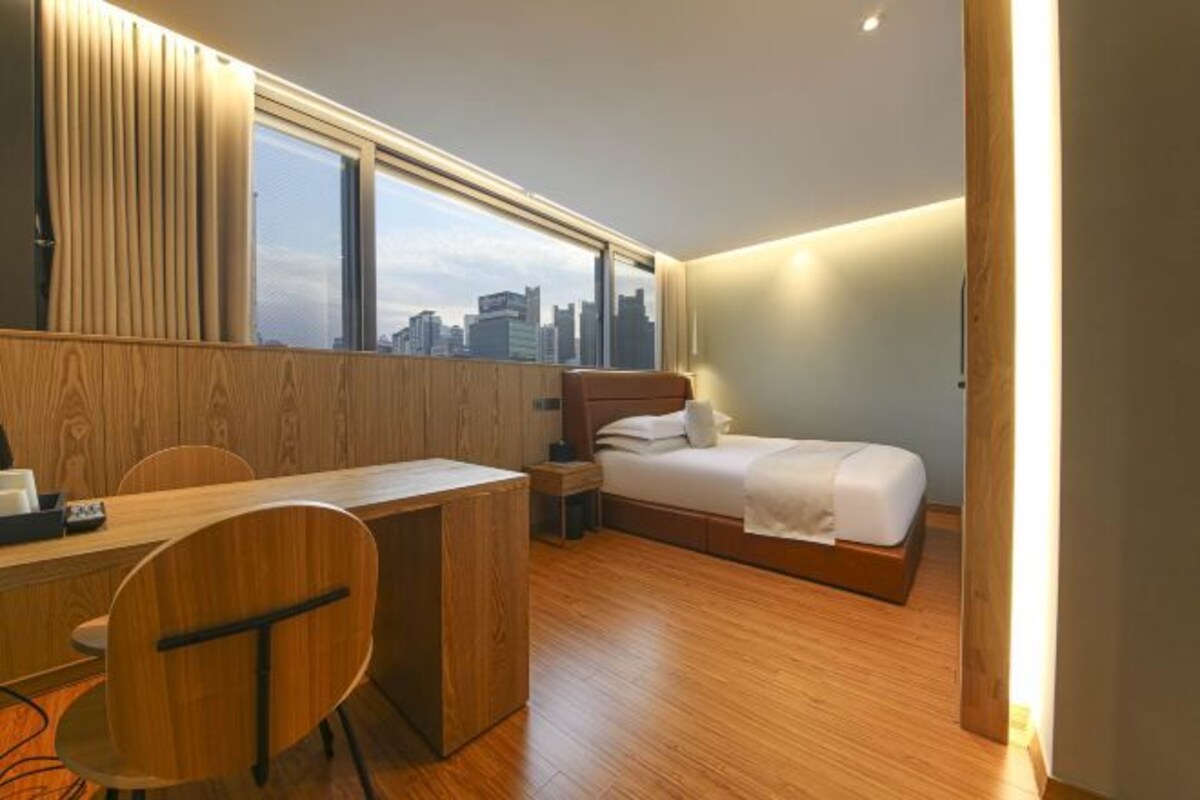 Une chambre d’hôtel avec un lit, un bureau, une chaise et une vue sur la ville.