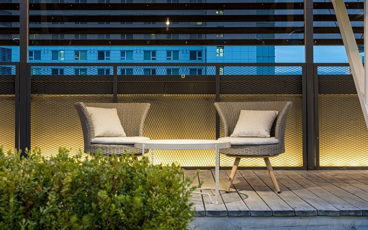 A modern outdoor seating area with a metal railing and a view of a building in the background.