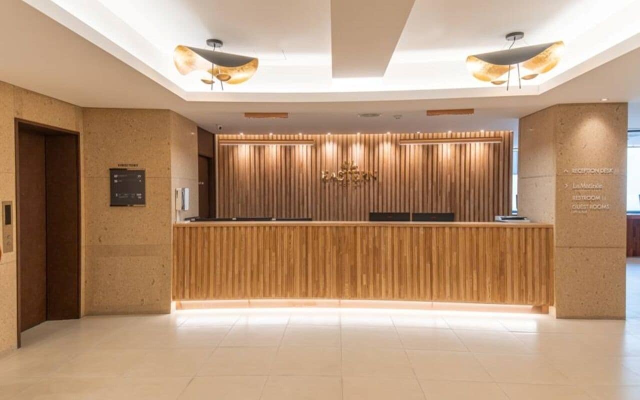 Un comptoir d’accueil avec un revêtement en bois, un panneau d’affichage numérique et un comptoir d’accueil doté d’un panneau décoratif en bois.
