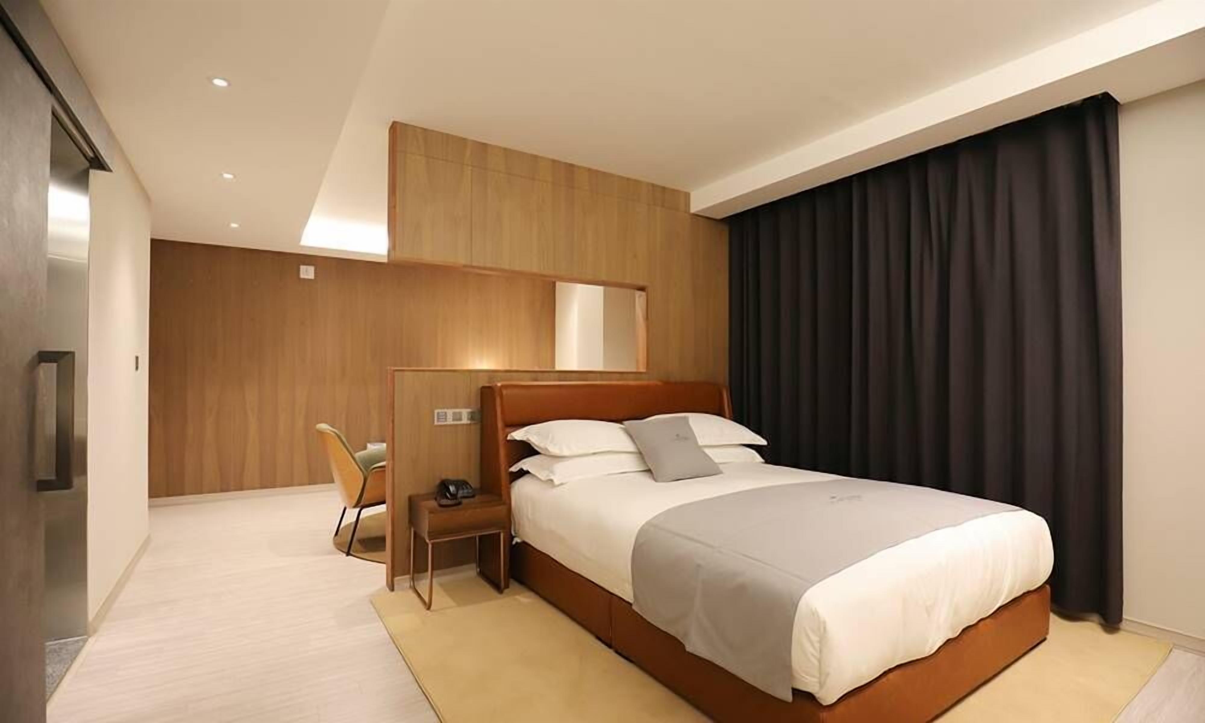 Ein modernes Hotelzimmer mit einem großen Bett, einem Schreibtisch und einem Stuhl.