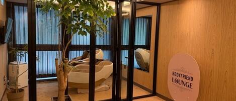 A room with a massage chair, a potted plant, and a sign indicating a bodyfriend lounge.