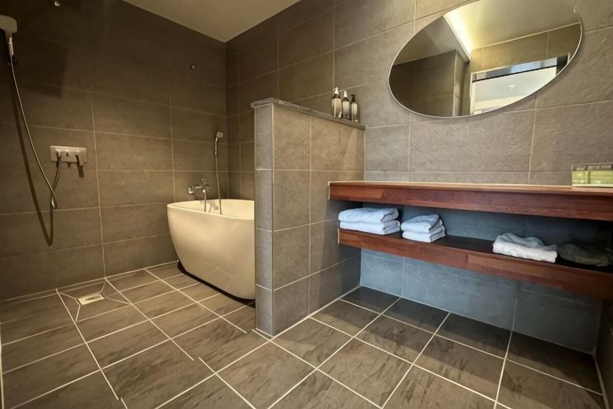 A modern bathroom with a bathtub, a shower, and a vanity with shelves.