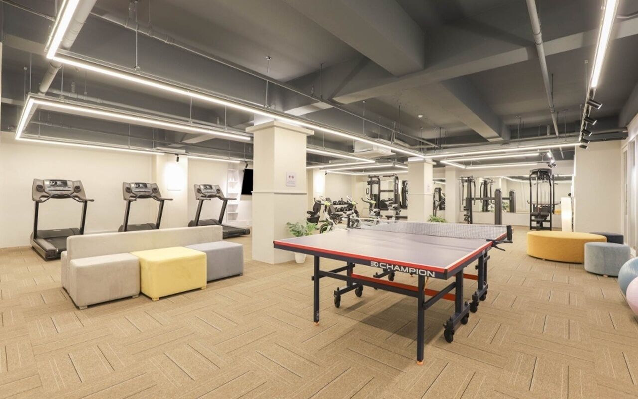 Un gimnasio con equipo de ejercicio, incluyendo cintas de correr, una bicicleta estática y una mesa de ping pong.