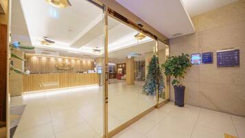 Et receptionområde med glasvæg, receptionistskranke, juletræ og skilt med vejvisning.