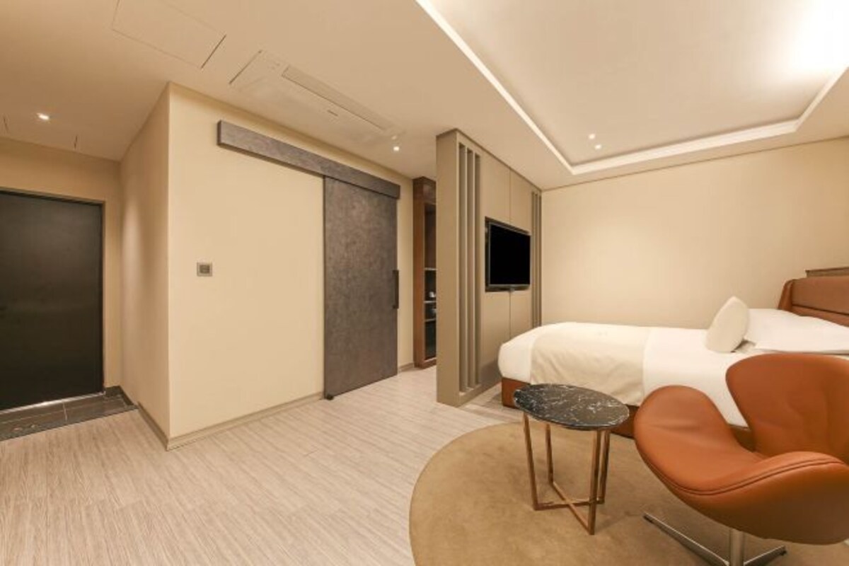 Une chambre d’hôtel avec un lit, une télévision, une chaise et un bureau.