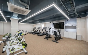 A gym with stationary bikes, treadmills, and a TV screen. - Dongdaegu Station Eastern Hotel (Daegu)