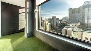 A room with a large window, a green artificial grass floor, and a view of a cityscape. - Dongdaegu Station Eastern Hotel (Daegu)