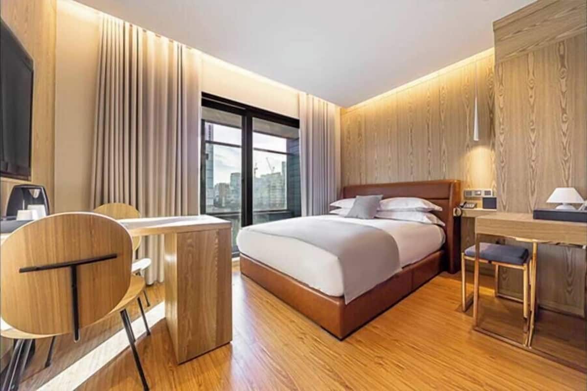 A modern hotel room with a large bed, a desk, and a chair.