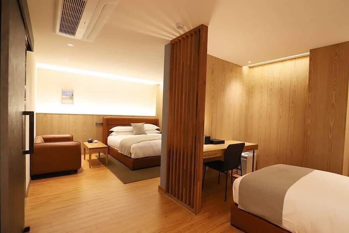 A hotel room with two beds, a desk, a chair, and a small table.