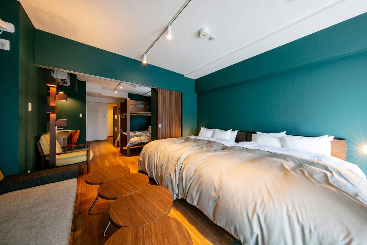 A modern hotel room with a large bed, a seating area with a small table, and a walk-in closet.