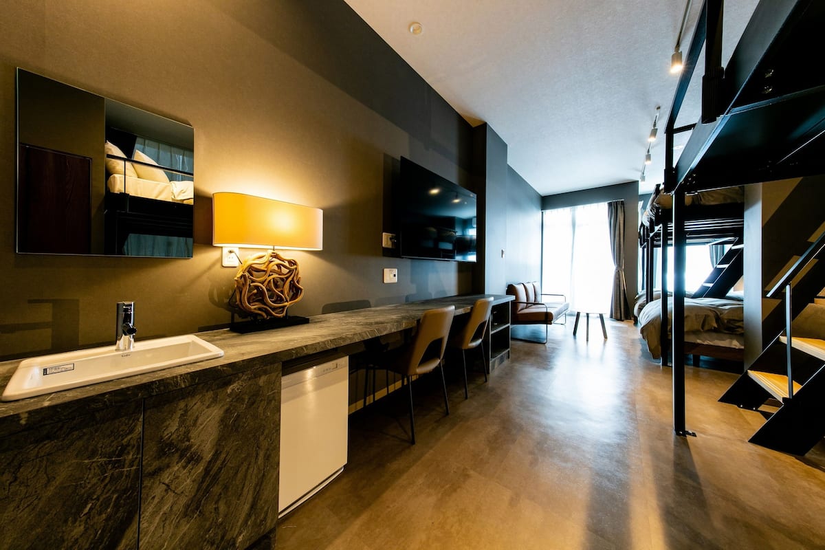 A modern kitchen with a marble countertop, built-in dishwasher, and a large mirror.