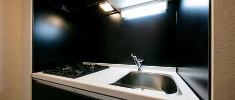 A modern kitchen with a stainless steel sink, a gas stove, and a range hood.
