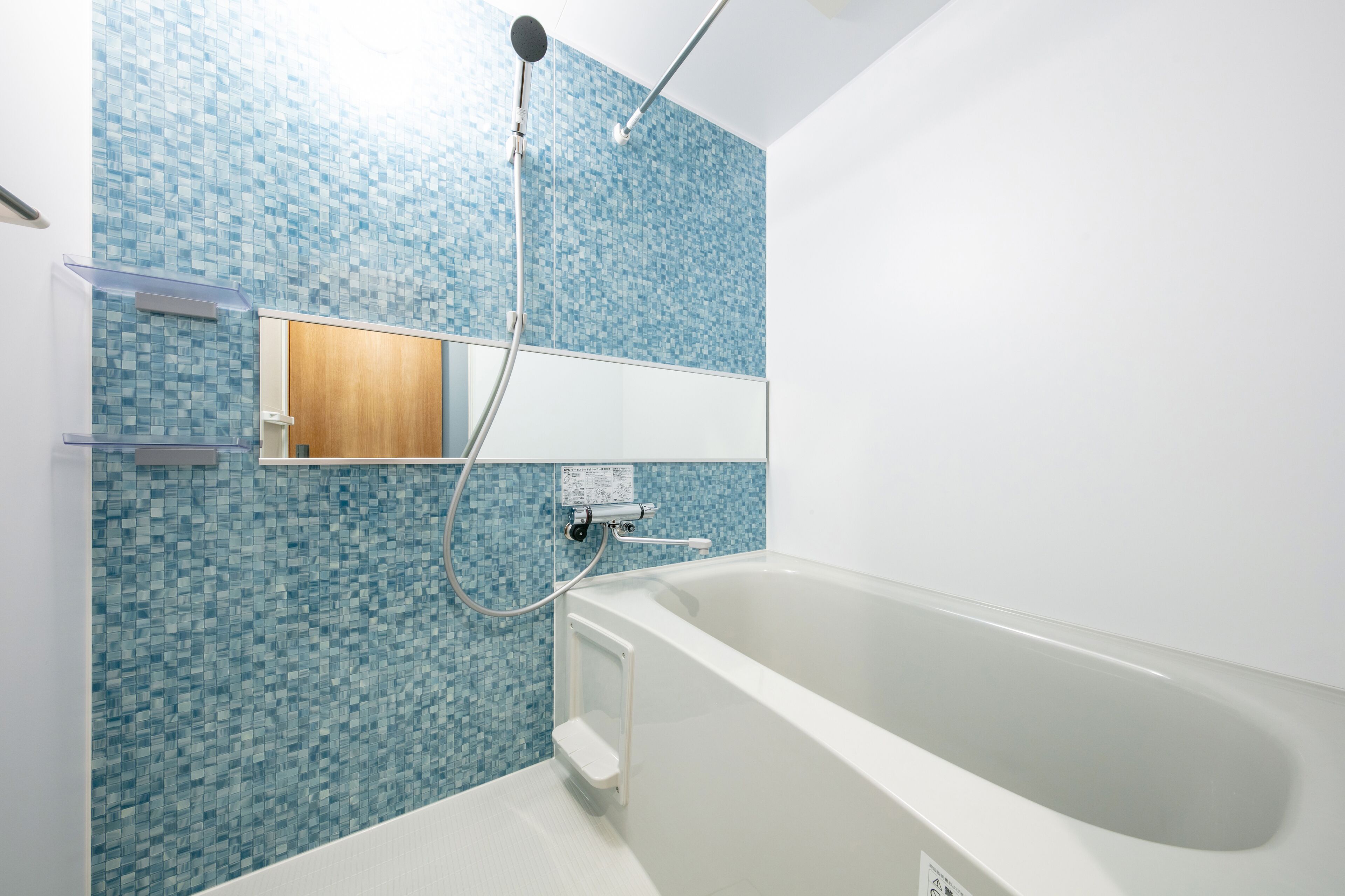 A modern bathroom with a large bathtub, a showerhead, and a tiled wall.
