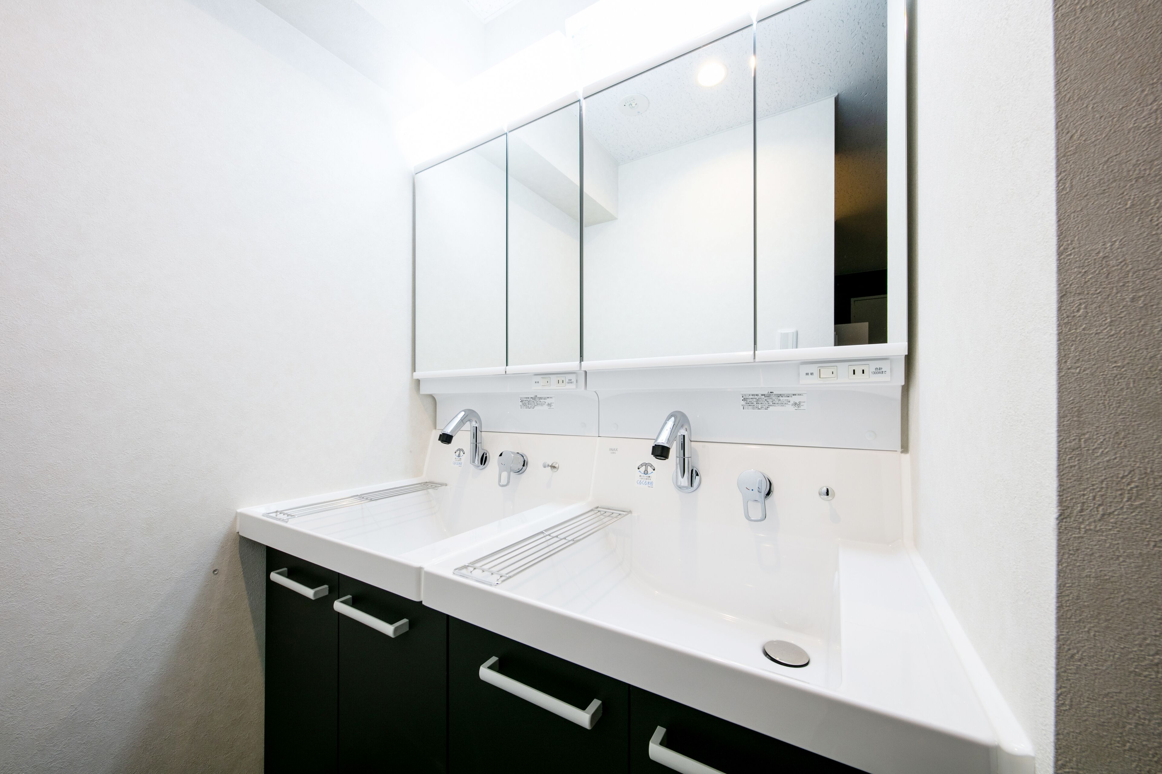 Une salle de bain moderne avec deux lavabos, un miroir et un porte-serviettes.